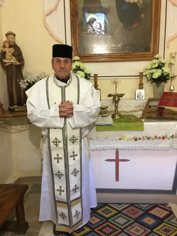 Sa Grâce Mgr Andrea de Lucia en habits liturgiques blancs, dans une chapelle